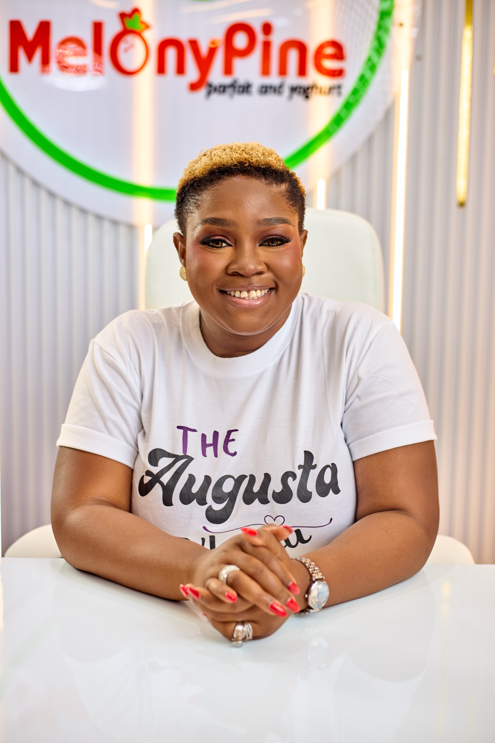 Augusta Nkanu seated at her MelonyPine desk in a white T-shirt